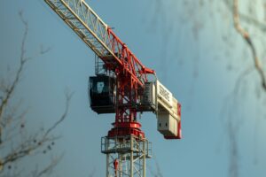 Close-up of a red tower crane with clear blue sky background, highlighting construction industry.